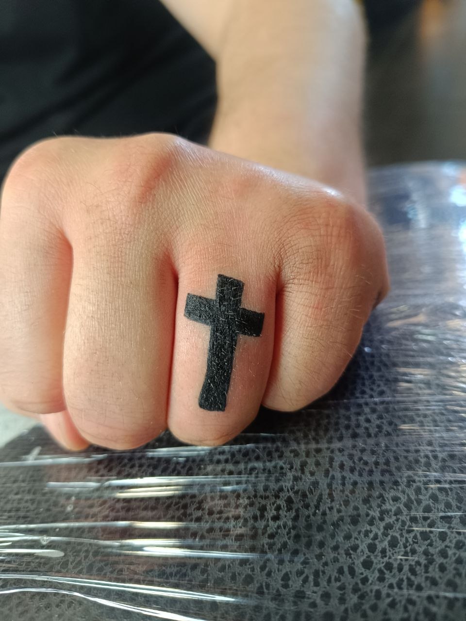 Schwarzes Kreuz tätowiert auf dem Finger