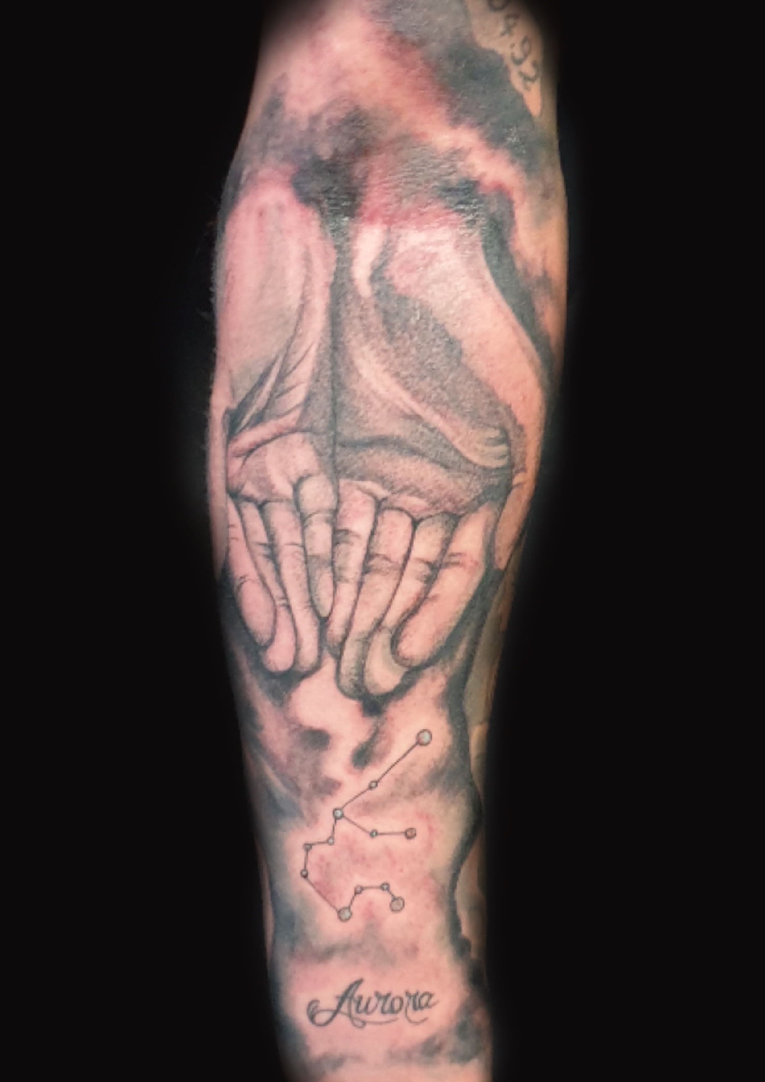 Tattoo von 2 Händen mit aurora Schriftzug und Sternkonstilation