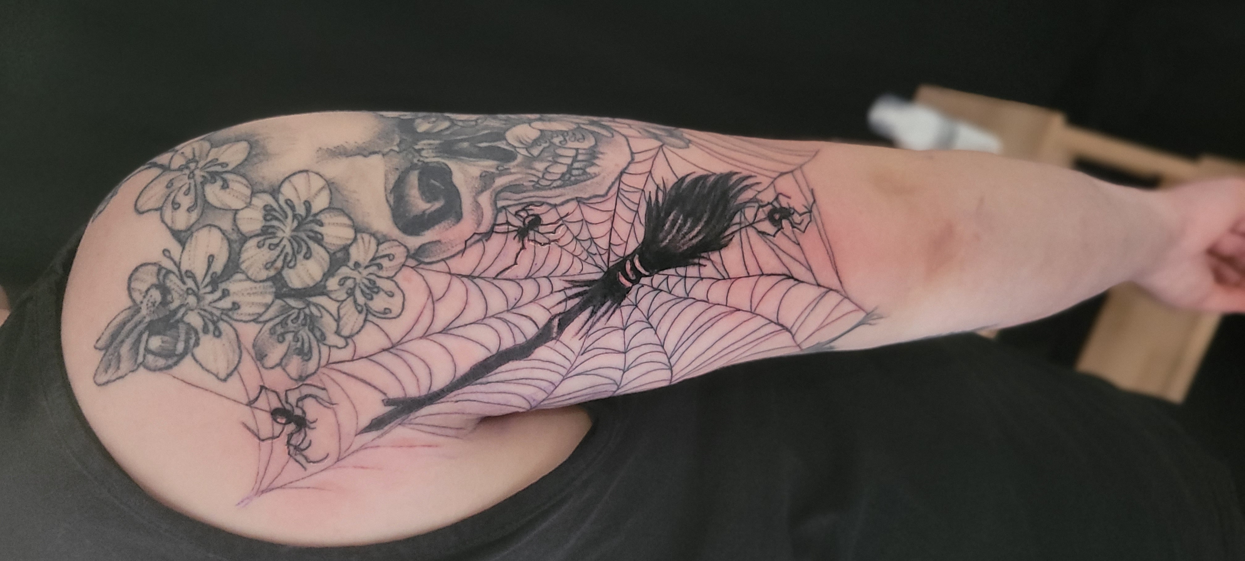 Tattoo von einem Spinnennetz mit Hexenbesen und Spinne in Schwarz Grau