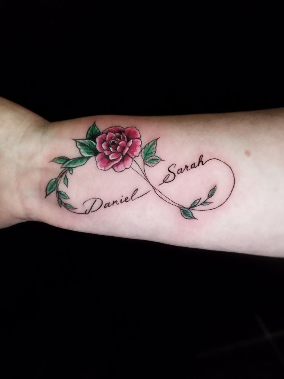 tattoo eines unendlichkeits symbols mit Namen und buter rose