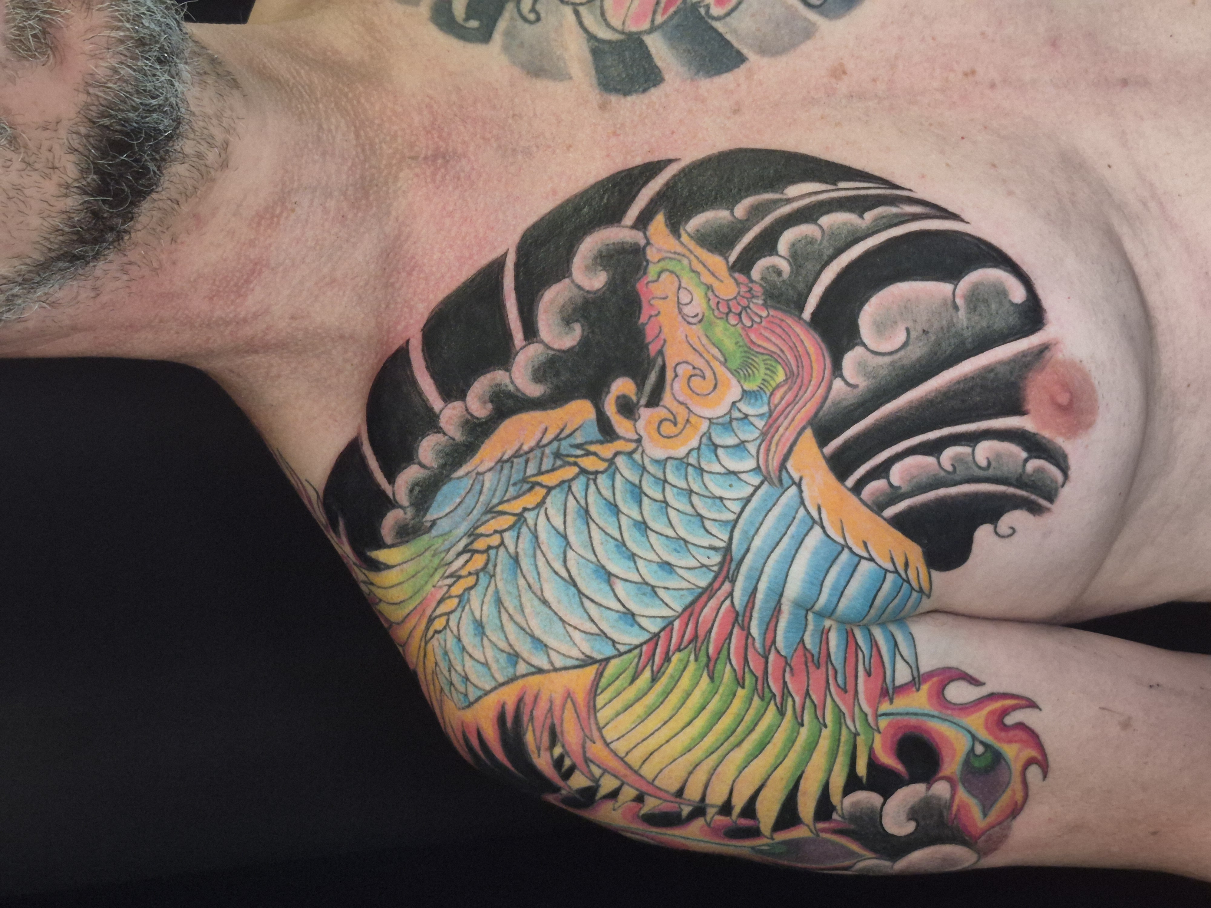 Tattoo von einem bunten Phönix auf Schulter